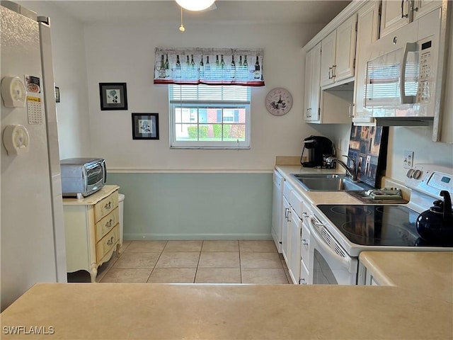 kitchen with white cabinetry, sink, light tile patterned flooring, and white appliances