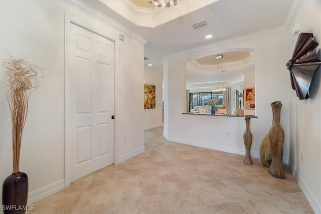 hallway with a tray ceiling and ornamental molding