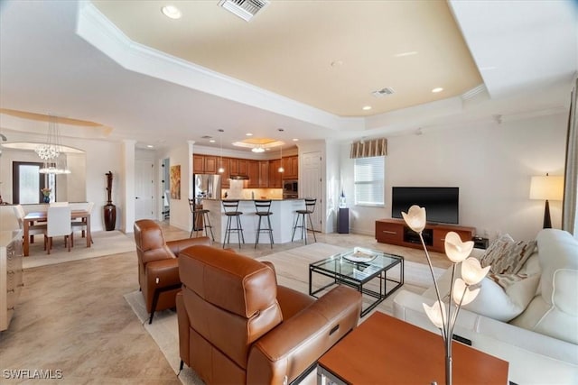 living room with crown molding, a raised ceiling, and a chandelier