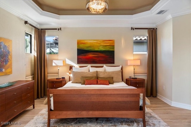 bedroom with crown molding, light hardwood / wood-style floors, and a tray ceiling