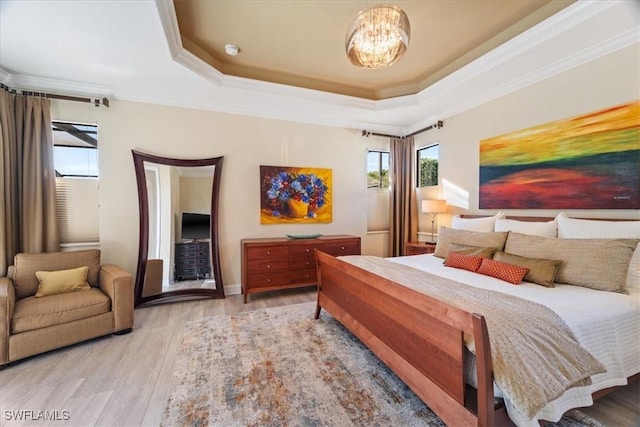 bedroom featuring a notable chandelier, ornamental molding, light hardwood / wood-style floors, and a raised ceiling