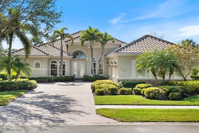 mediterranean / spanish house with a front yard and french doors