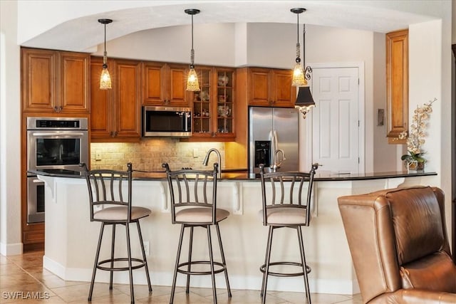 kitchen featuring appliances with stainless steel finishes, decorative light fixtures, and a kitchen breakfast bar