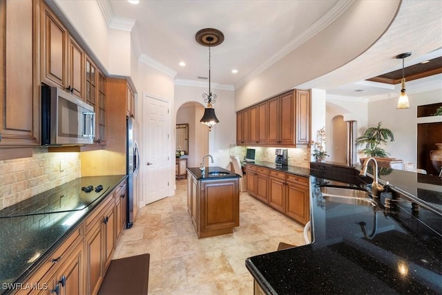 kitchen with stainless steel appliances, a center island with sink, sink, and pendant lighting