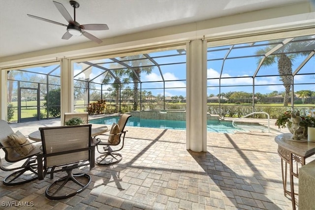 view of swimming pool with ceiling fan, pool water feature, glass enclosure, and a patio area