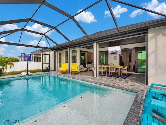 view of swimming pool with a patio, outdoor lounge area, ceiling fan, and glass enclosure