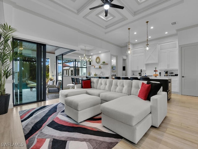 living room with ceiling fan with notable chandelier, light wood-type flooring, coffered ceiling, crown molding, and beam ceiling