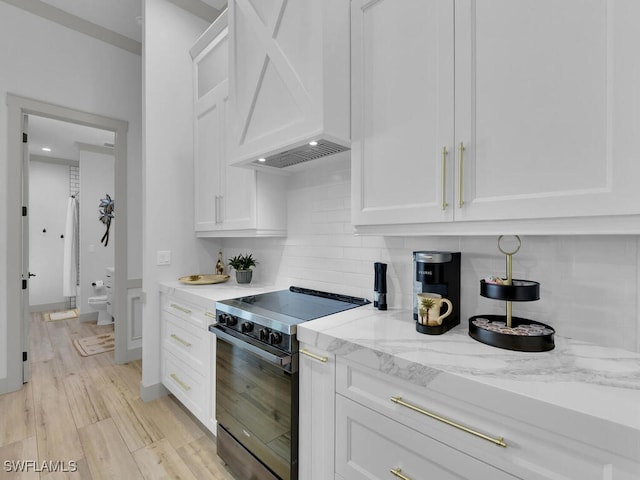 kitchen featuring white cabinetry, custom exhaust hood, light stone counters, and electric range oven