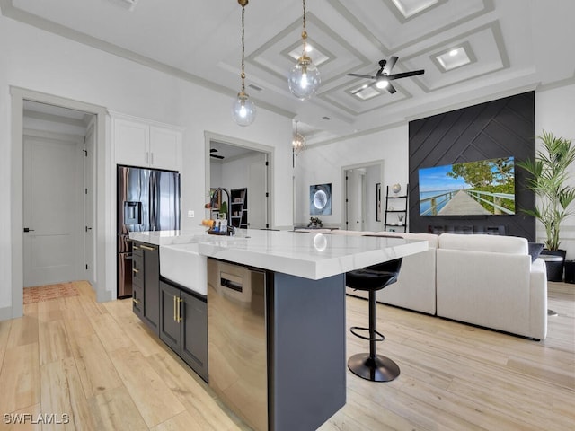 kitchen with white cabinetry, stainless steel appliances, coffered ceiling, an island with sink, and decorative light fixtures