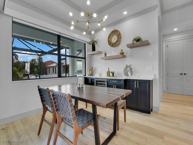 dining space featuring indoor bar, wine cooler, an inviting chandelier, and light hardwood / wood-style flooring