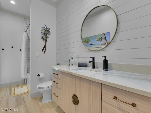 full bathroom featuring toilet, vanity, shower / bathtub combination with curtain, wooden walls, and hardwood / wood-style floors