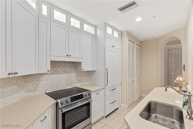 kitchen with light tile patterned floors, white cabinetry, electric range, and sink