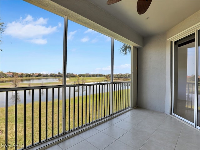 unfurnished sunroom featuring ceiling fan and a water view