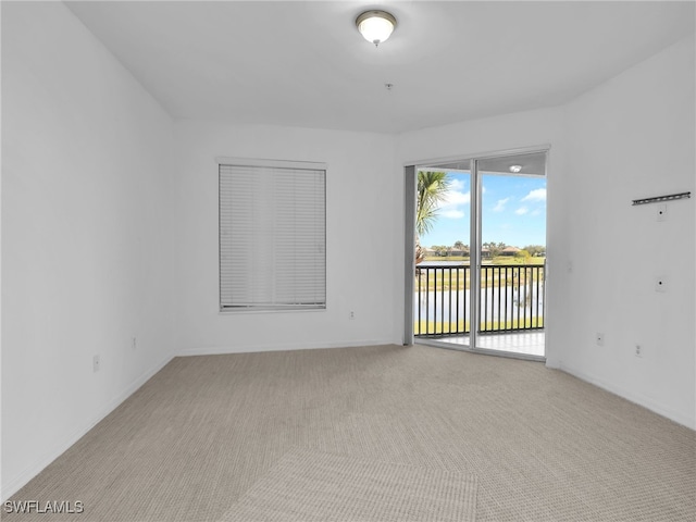 spare room featuring light carpet and a water view