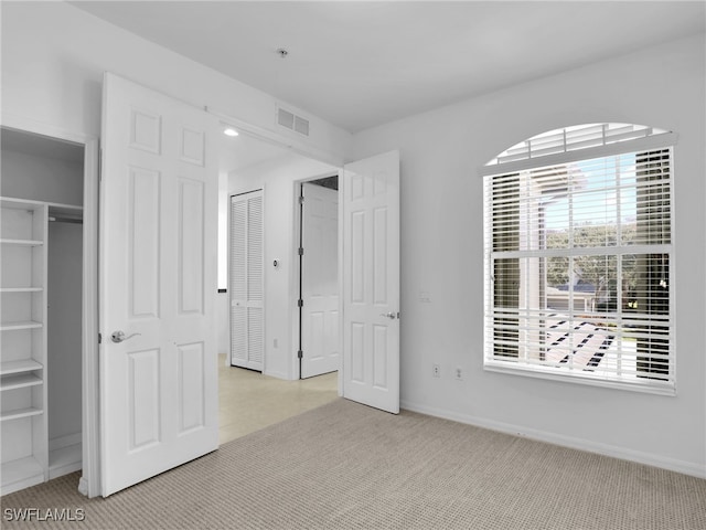 unfurnished bedroom featuring light colored carpet and a closet