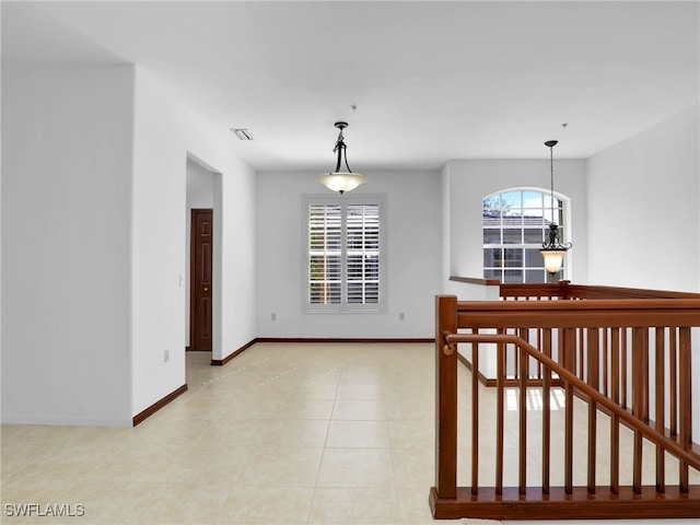 tiled empty room with an inviting chandelier