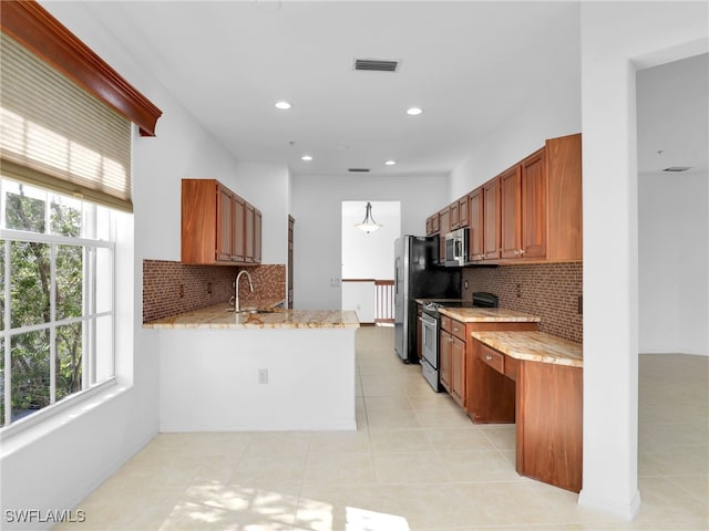 kitchen with sink, appliances with stainless steel finishes, kitchen peninsula, a wealth of natural light, and light stone countertops