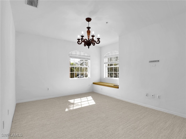 empty room featuring light carpet and a notable chandelier