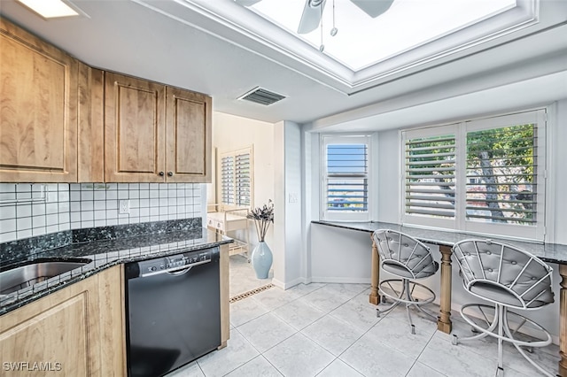 kitchen with light tile patterned floors, dishwasher, ceiling fan, dark stone countertops, and backsplash