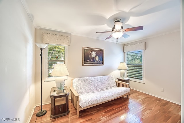 living area featuring ornamental molding, wood-type flooring, and ceiling fan