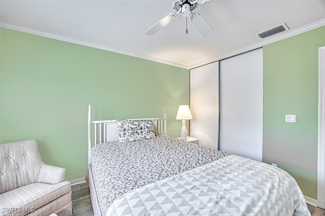 bedroom with ornamental molding, hardwood / wood-style floors, ceiling fan, and a closet