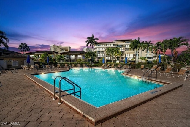 pool at dusk featuring a patio