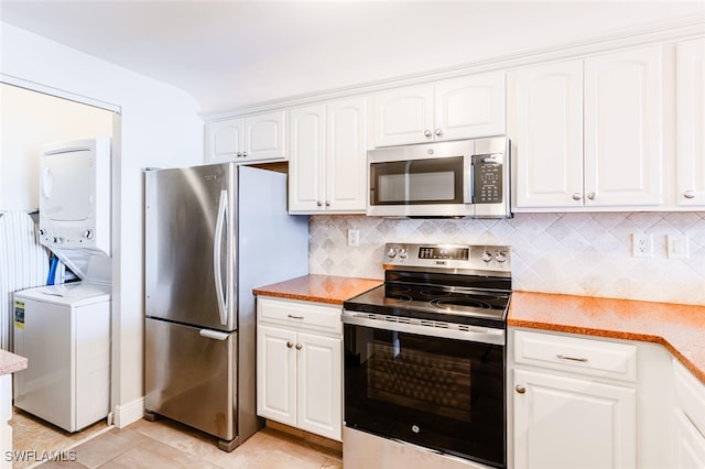 kitchen featuring white cabinetry, light tile patterned floors, stainless steel appliances, stacked washing maching and dryer, and decorative backsplash