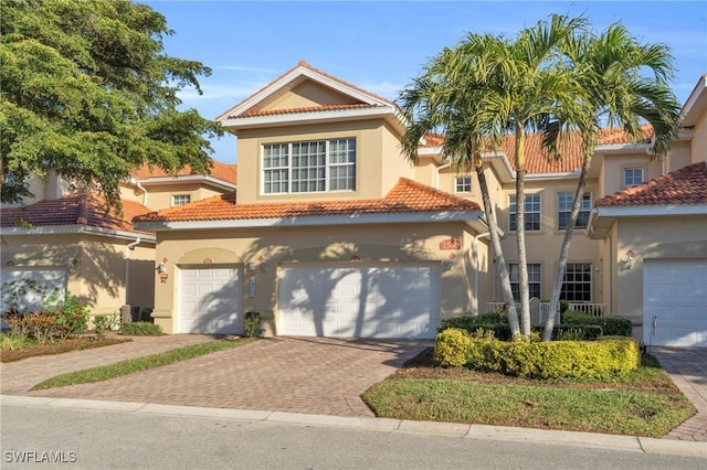 mediterranean / spanish house with decorative driveway, a tile roof, and stucco siding