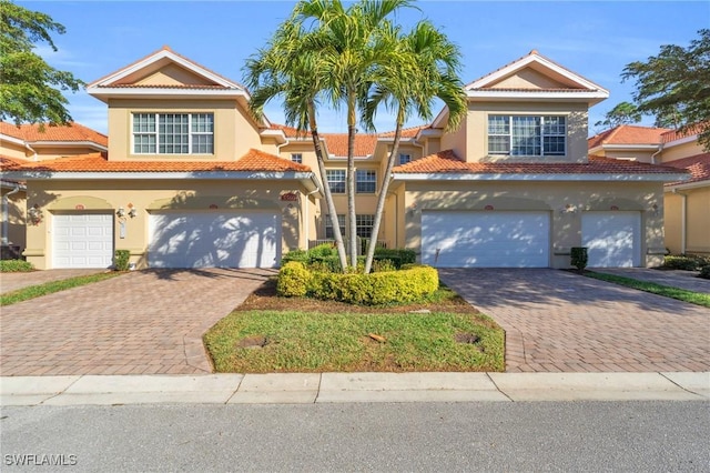 view of front of property featuring a garage, decorative driveway, and a tiled roof