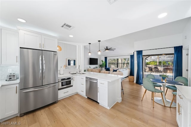 kitchen with sink, white cabinetry, decorative light fixtures, appliances with stainless steel finishes, and kitchen peninsula