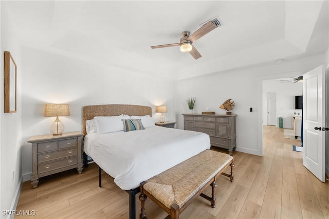 bedroom featuring ceiling fan, a raised ceiling, and light hardwood / wood-style flooring