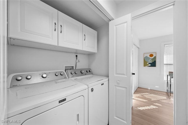 washroom featuring separate washer and dryer, cabinets, and light wood-type flooring