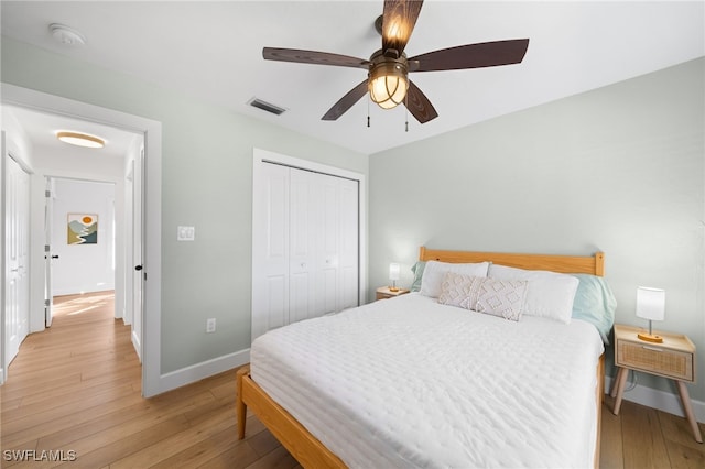 bedroom with light hardwood / wood-style flooring, ceiling fan, and a closet