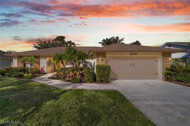 ranch-style home with a garage and a lawn