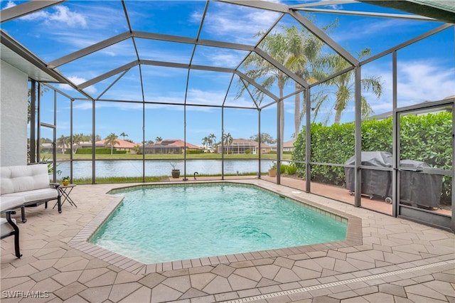 view of pool featuring glass enclosure, a water view, and a patio