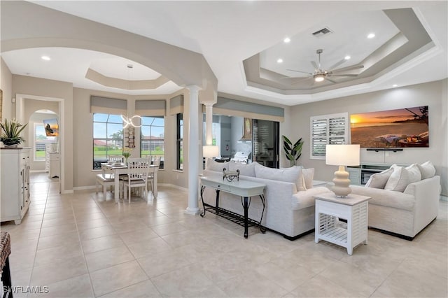 living room featuring a raised ceiling, light tile patterned floors, and ceiling fan