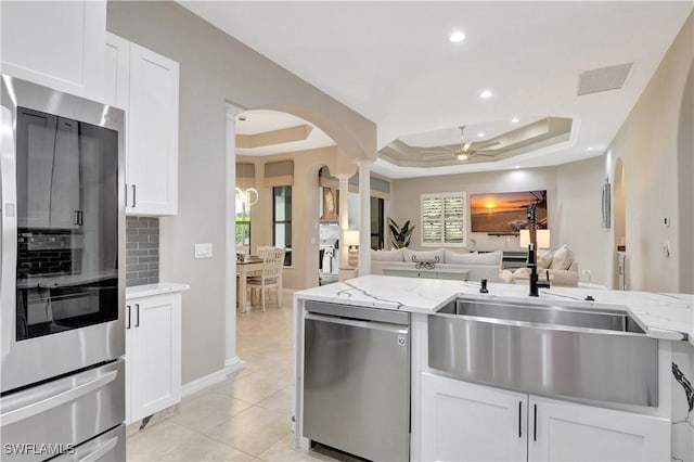 kitchen featuring light stone counters, white cabinetry, a tray ceiling, and appliances with stainless steel finishes