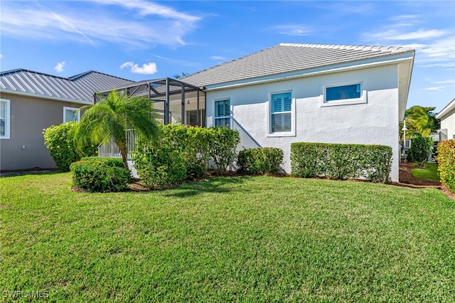 view of side of property with a lanai and a lawn