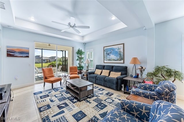 living room featuring a tray ceiling, ceiling fan, and light tile patterned flooring