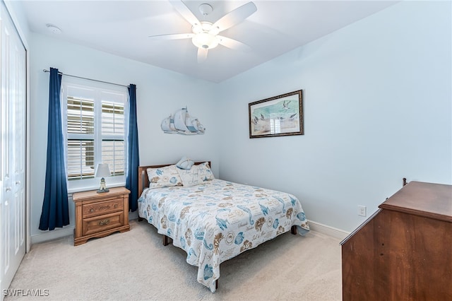 bedroom featuring light colored carpet, ceiling fan, and a closet