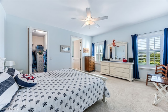 carpeted bedroom with ceiling fan, a spacious closet, and a closet