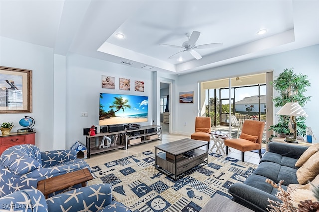 tiled living room with a raised ceiling and ceiling fan