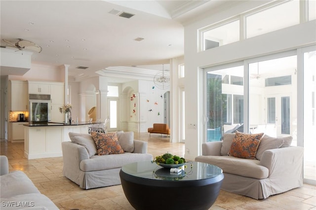 living room featuring a chandelier, crown molding, and a high ceiling