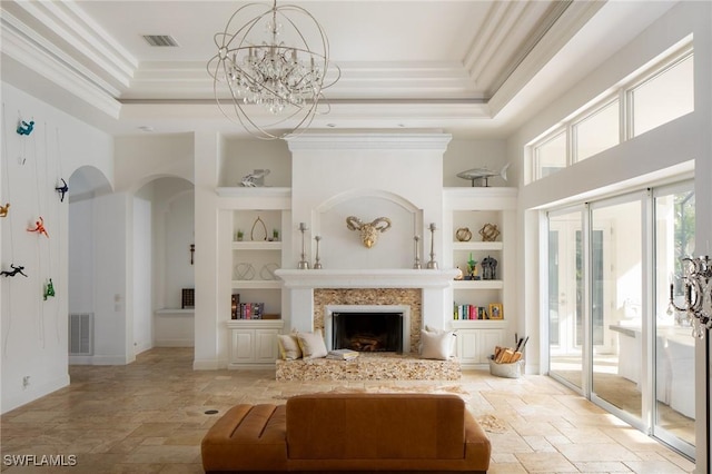 living room with a high ceiling, built in shelves, an inviting chandelier, a raised ceiling, and crown molding