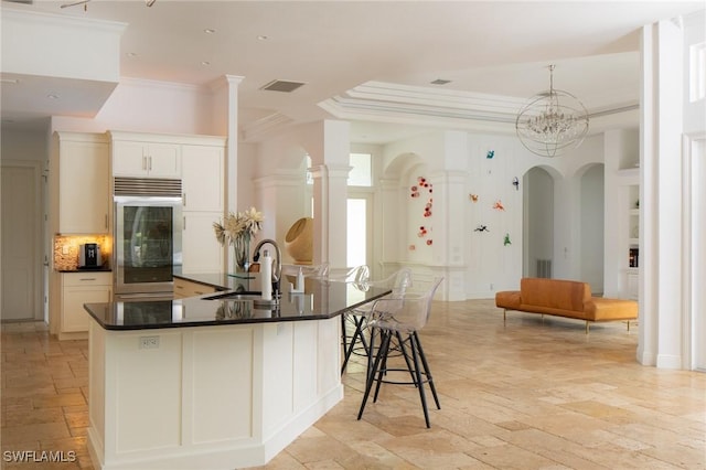 kitchen featuring high quality fridge, white cabinets, sink, backsplash, and a kitchen breakfast bar