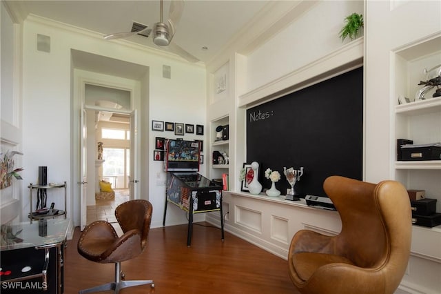 sitting room featuring ceiling fan, dark wood-type flooring, built in features, and crown molding