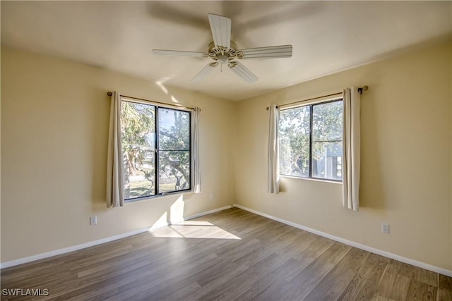 spare room featuring wood-type flooring, a healthy amount of sunlight, and ceiling fan