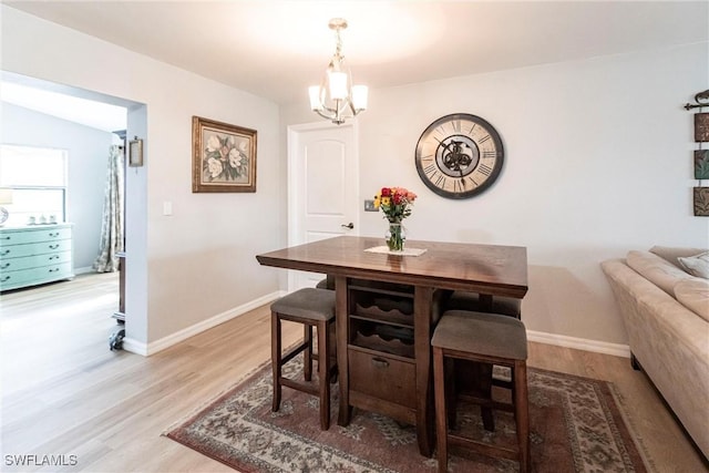 dining room with an inviting chandelier, lofted ceiling, and light hardwood / wood-style flooring