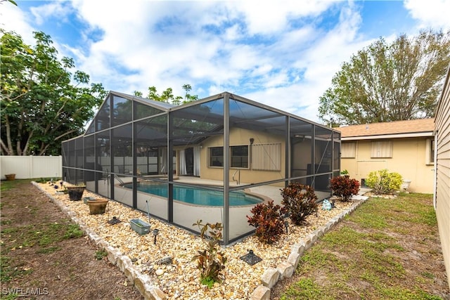 rear view of house with a lanai, a patio area, and a fenced in pool