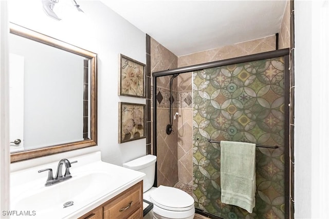 bathroom featuring toilet, vanity, and an enclosed shower